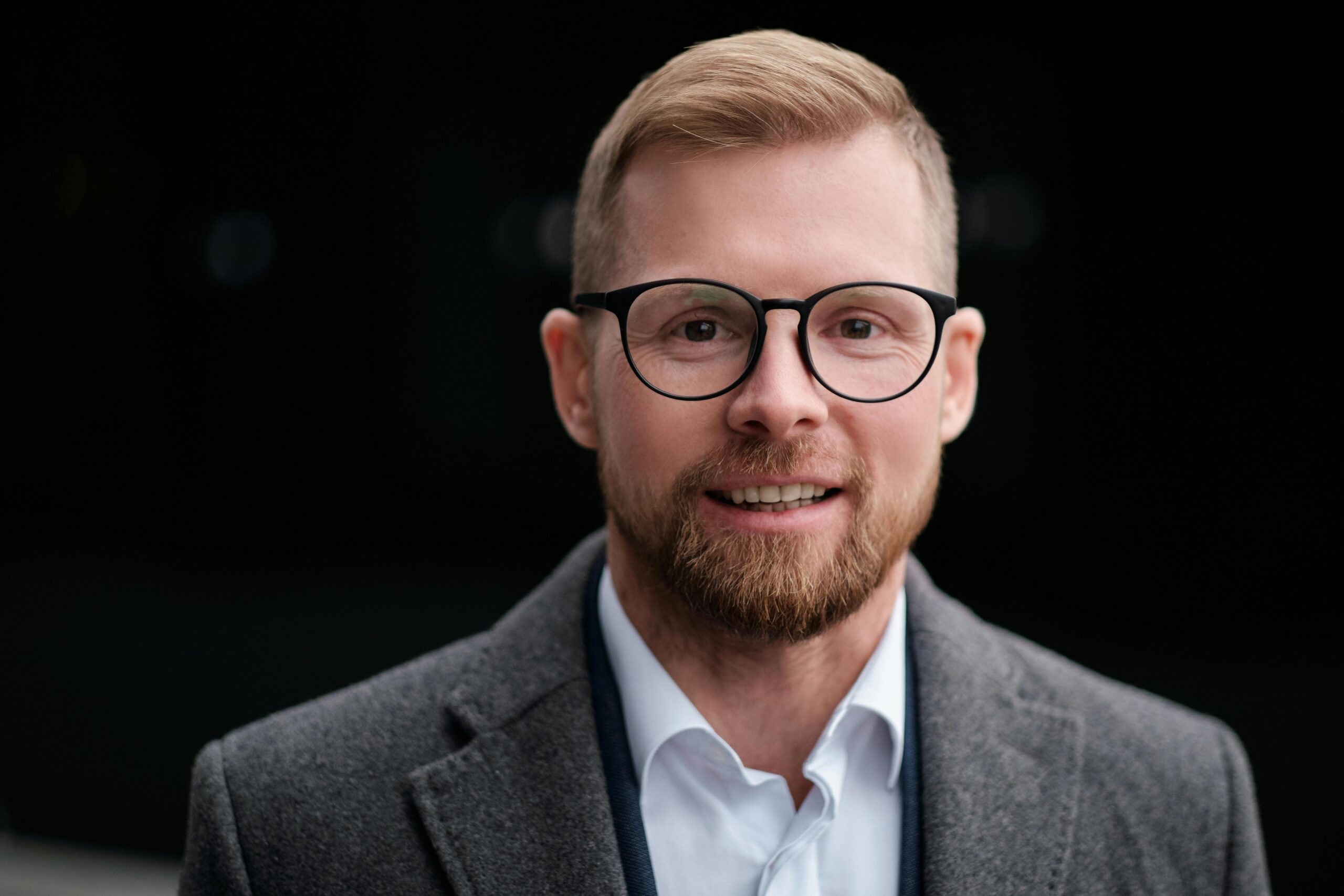 Close-up of a smiling businessman with a beard and glasses.